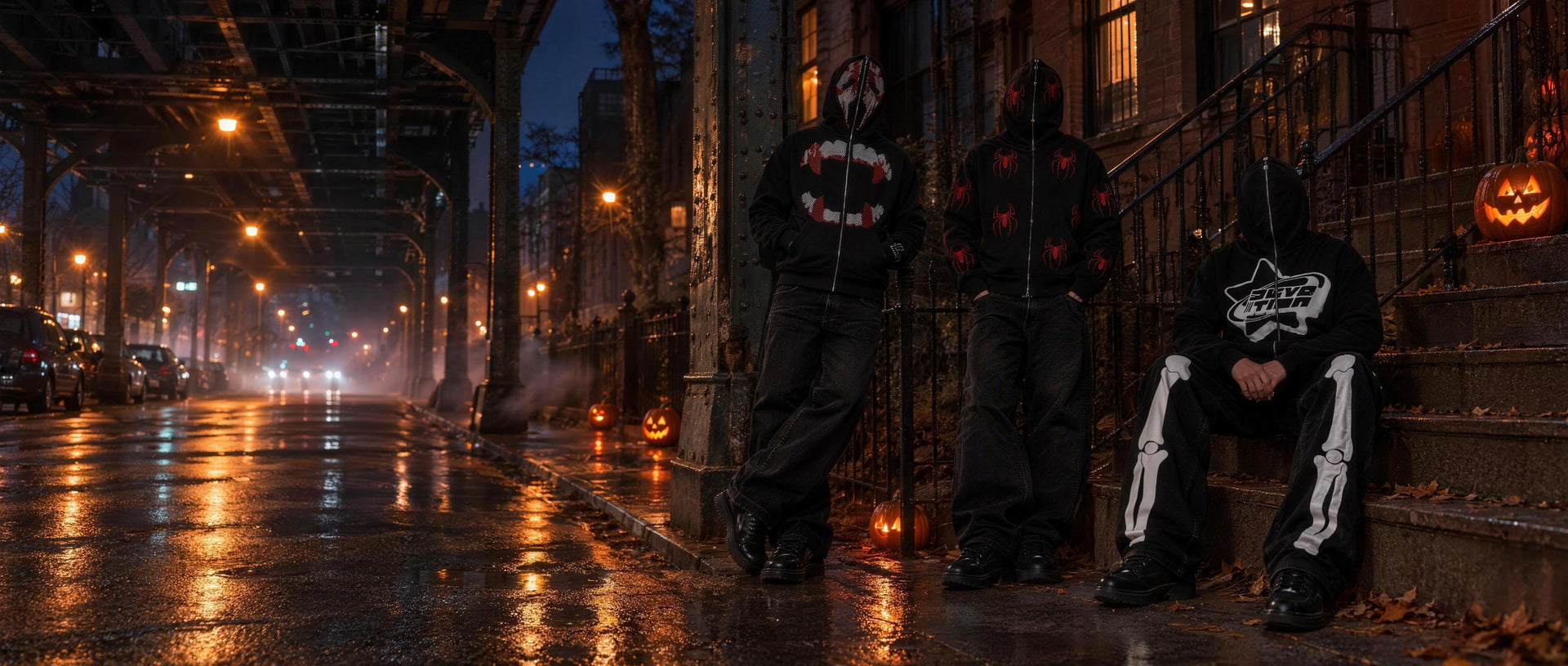 Y2K Crew Halloween campaign: three models under a New York elevated subway at night with jack-o-lanterns, hoods zipped over their faces, wearing the Rhinestone Scream full zip, the Spiderman full zip and the Devotion full zip with skeleton pants